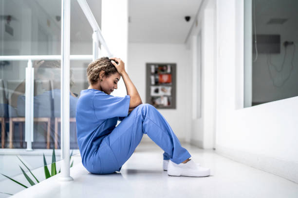 Female nurse sitting on the floor and looking distraught