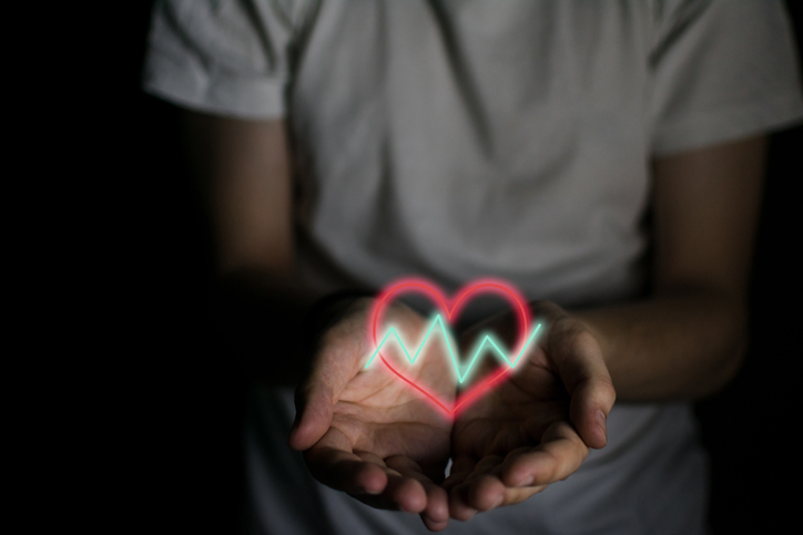 Heart with fluctuating lines on a man's hands. Health concept.