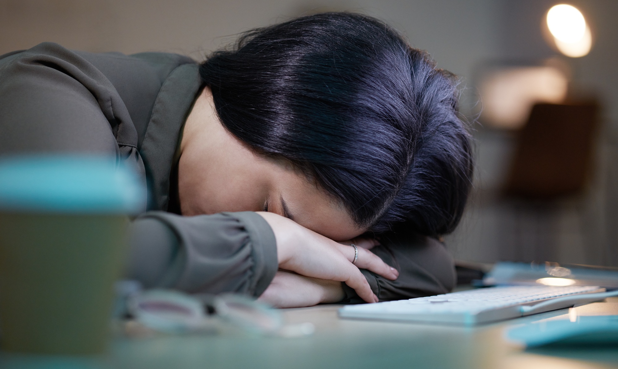 tired sleeping woman at her computer at night for depression burnout and mental health risk busi